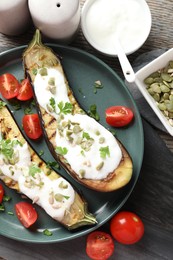 Photo of Slices of grilled eggplant with pumpkin seeds, tomatoes and yoghurt on wooden table, flat lay