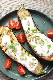 Photo of Slices of grilled eggplant with pumpkin seeds, tomatoes and yoghurt on wooden table, top view