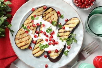 Photo of Slices of grilled eggplant with pomegranate seeds and yoghurt on white marble table, flat lay