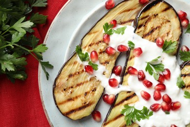 Photo of Slices of grilled eggplant with pomegranate seeds and yoghurt on table, flat lay