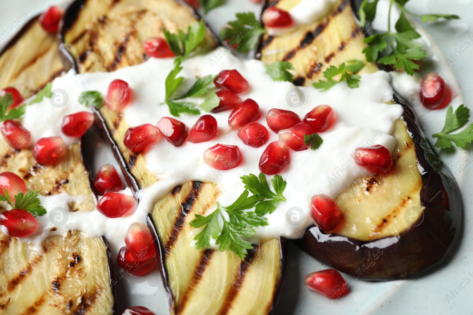 Slices of grilled eggplant with pomegranate seeds and yoghurt on table Photo of Slices of grilled eggplant with pomegranate seeds and yoghurt on table