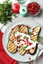 Photo of Slices of grilled eggplant with pomegranate seeds and yoghurt on white marble table, flat lay