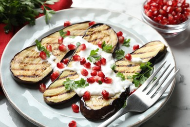 Photo of Slices of grilled eggplant with pomegranate seeds and yoghurt on white marble table, closeup