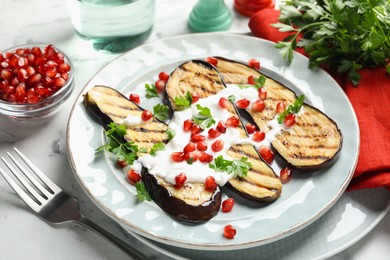 Photo of Slices of grilled eggplant with pomegranate seeds and yoghurt on white marble table, closeup