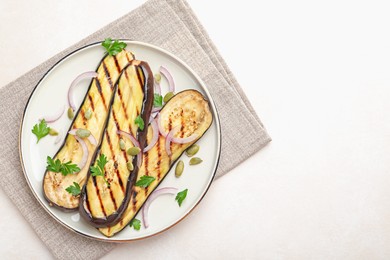 Photo of Slices of grilled eggplant, parsley, pumpkin seeds and onion on white table, top view. Space for text