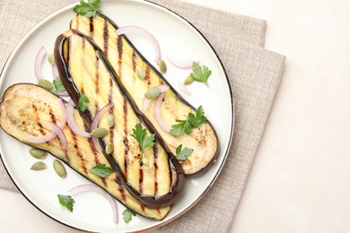 Photo of Slices of grilled eggplant, parsley, pumpkin seeds and onion on white table, top view. Space for text