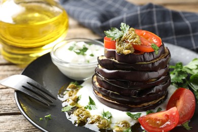 Photo of Tasty grilled eggplant slices with tomatoes, pesto and yoghurt on wooden table, closeup