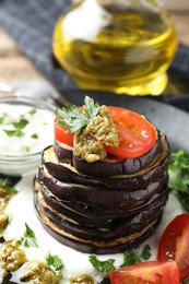 Photo of Tasty grilled eggplant slices with tomatoes, pesto and yoghurt on table, closeup