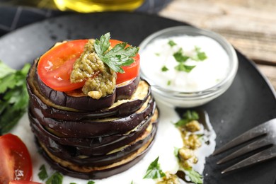 Photo of Tasty grilled eggplant slices with tomatoes, pesto and yoghurt on wooden table, closeup