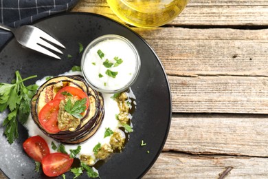 Photo of Tasty grilled eggplant slices with tomatoes, pesto and yoghurt on wooden table, flat lay. Space for text
