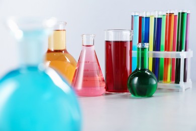 Photo of Different laboratory glassware with color liquids on light background, closeup