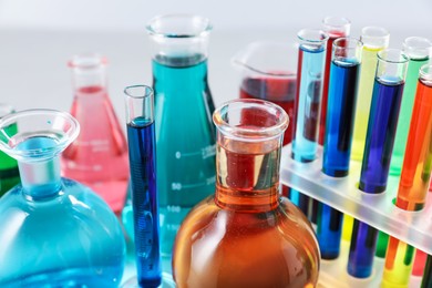 Photo of Different laboratory glassware with color liquids on light background, closeup