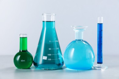 Photo of Different laboratory glassware with color liquids on light background