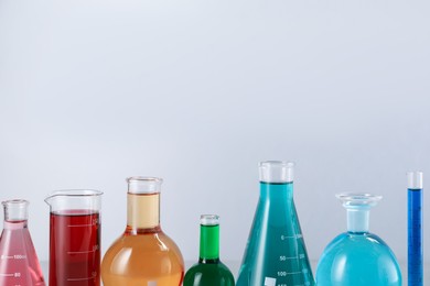 Photo of Different laboratory glassware with color liquids on light background. Space for text
