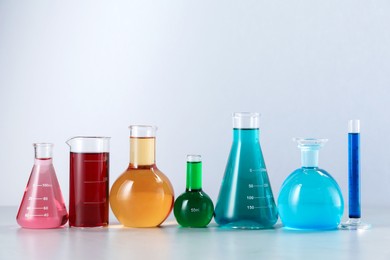 Photo of Different laboratory glassware with color liquids on light background