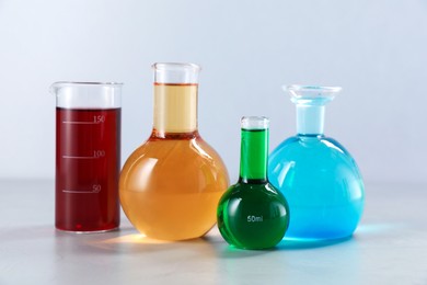 Photo of Different laboratory glassware with color liquids on light background