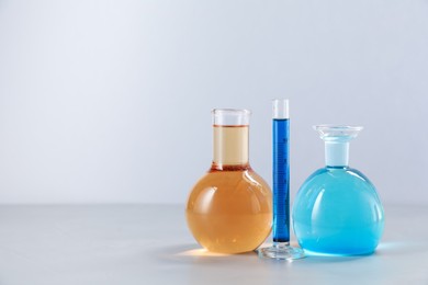 Photo of Different laboratory glassware with color liquids on light background. Space for text