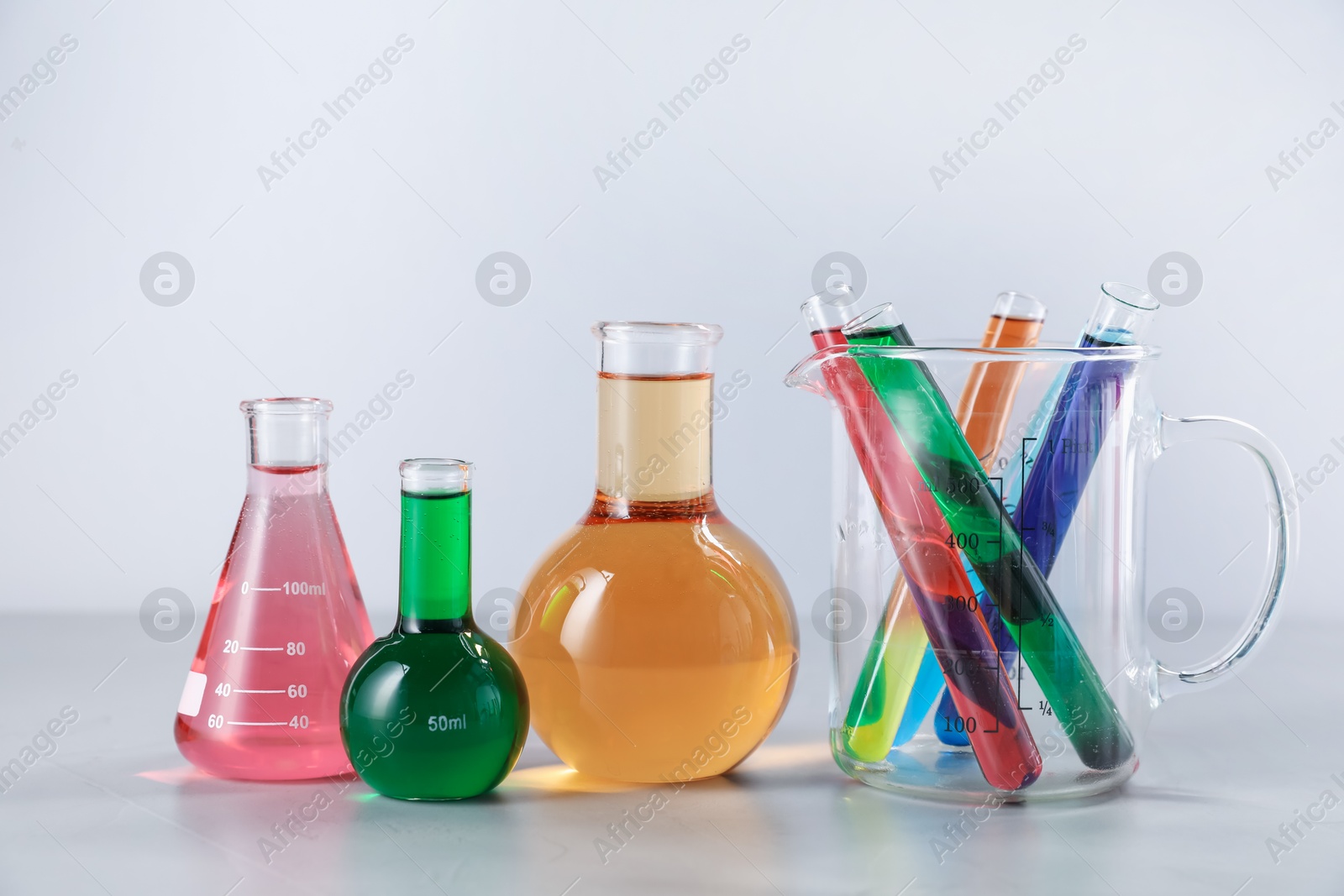 Different laboratory glassware with color liquids on light background Photo of Different laboratory glassware with color liquids on light background