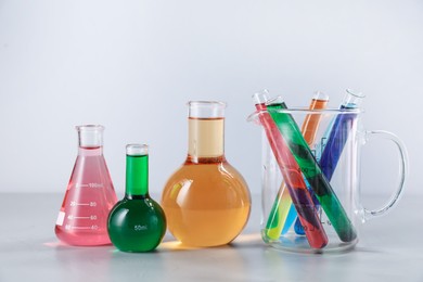 Photo of Different laboratory glassware with color liquids on light background