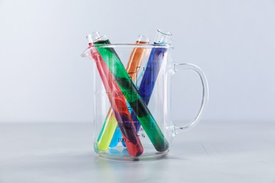 Photo of Test tubes with color liquids and beaker on light background