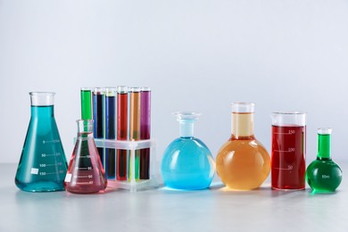 Photo of Different laboratory glassware with color liquids on light background
