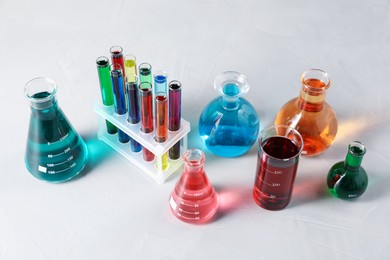 Photo of Different laboratory glassware with color liquids on light table