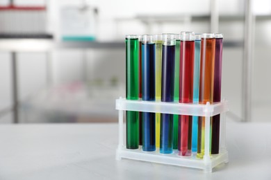 Photo of Test tubes with color liquids on light table in laboratory. Space for text