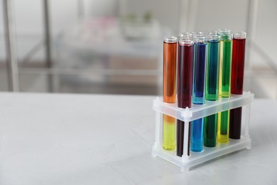 Photo of Test tubes with color liquids on light table in laboratory. Space for text