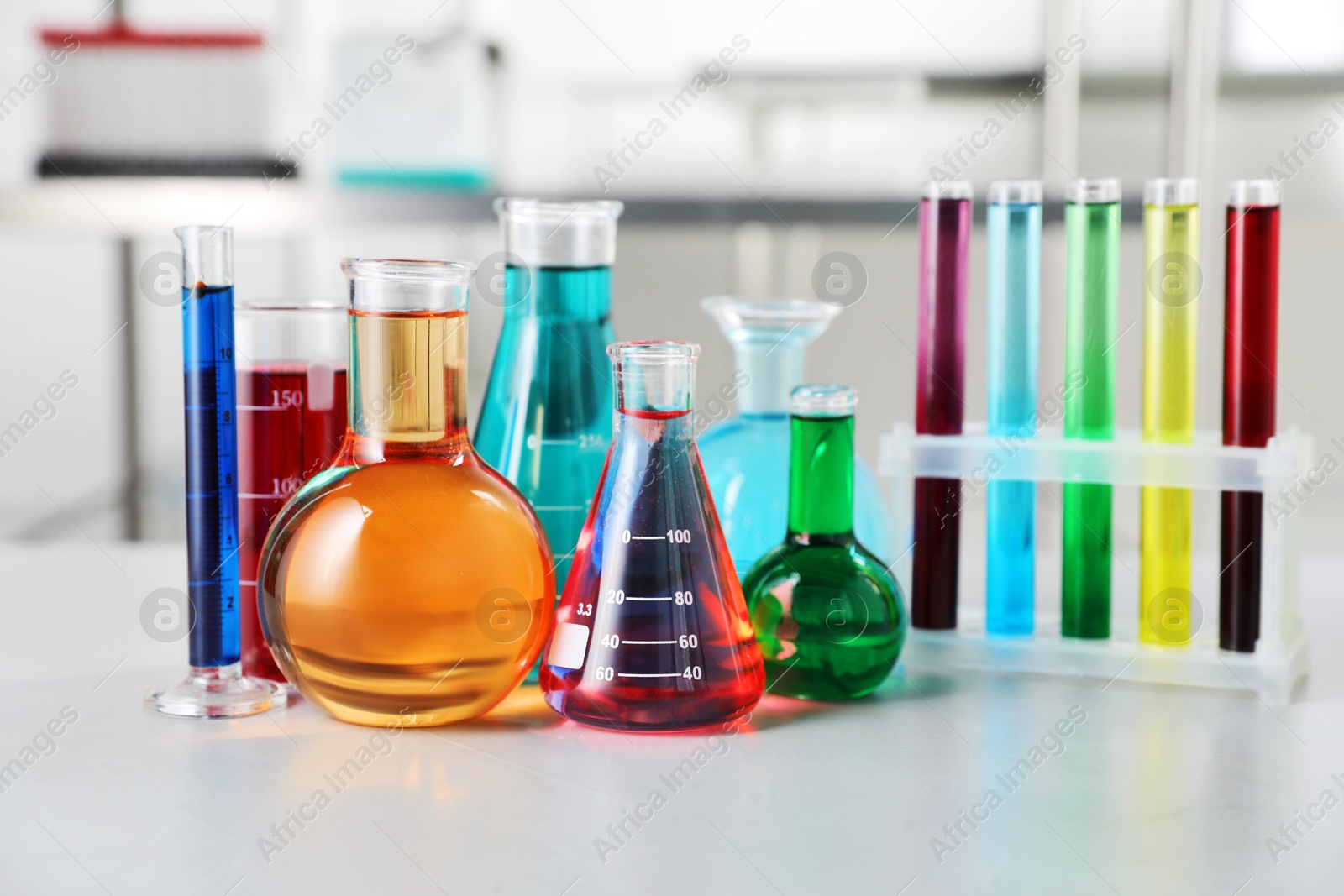 Different laboratory glassware with color liquids on light table indoors Photo of Different laboratory glassware with color liquids on light table indoors