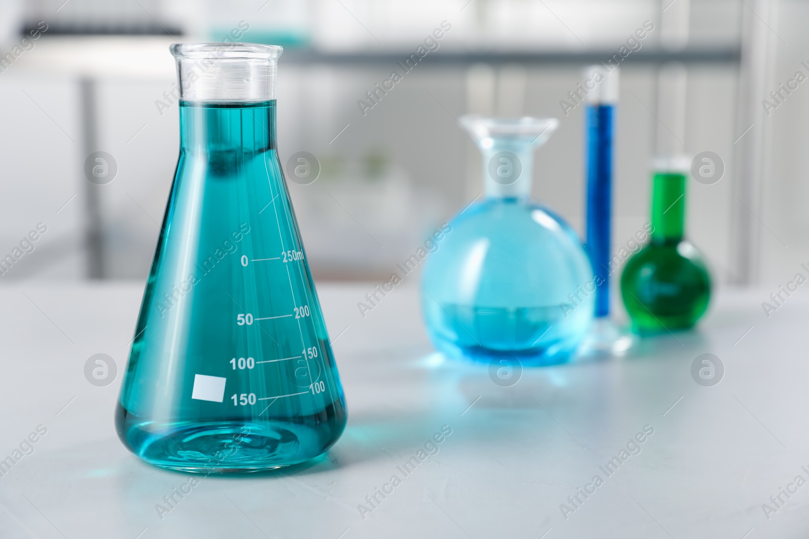 Different laboratory glassware with color liquids on light table indoors, selective focus Photo of Different laboratory glassware with color liquids on light table indoors, selective focus