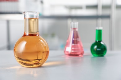 Photo of Different laboratory glassware with color liquids on light table indoors, selective focus