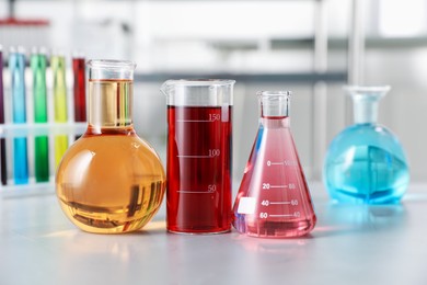 Photo of Different laboratory glassware with color liquids on light table indoors