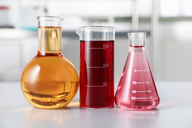 Photo of Different laboratory glassware with color liquids on light table indoors
