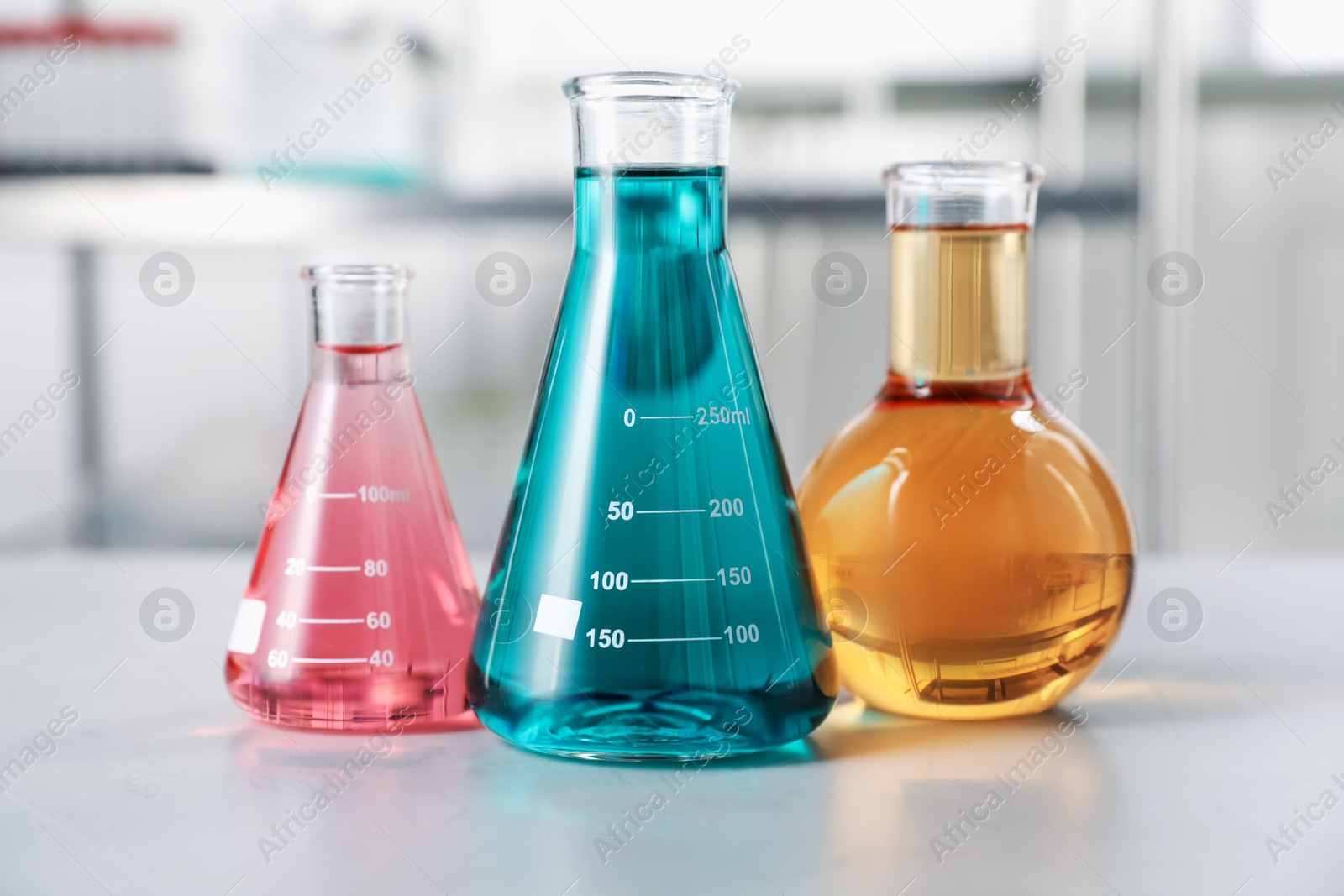 Different laboratory glassware with color liquids on light table indoors Photo of Different laboratory glassware with color liquids on light table indoors