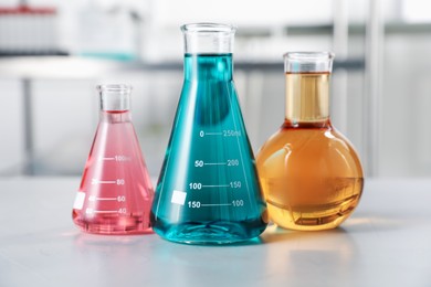 Photo of Different laboratory glassware with color liquids on light table indoors