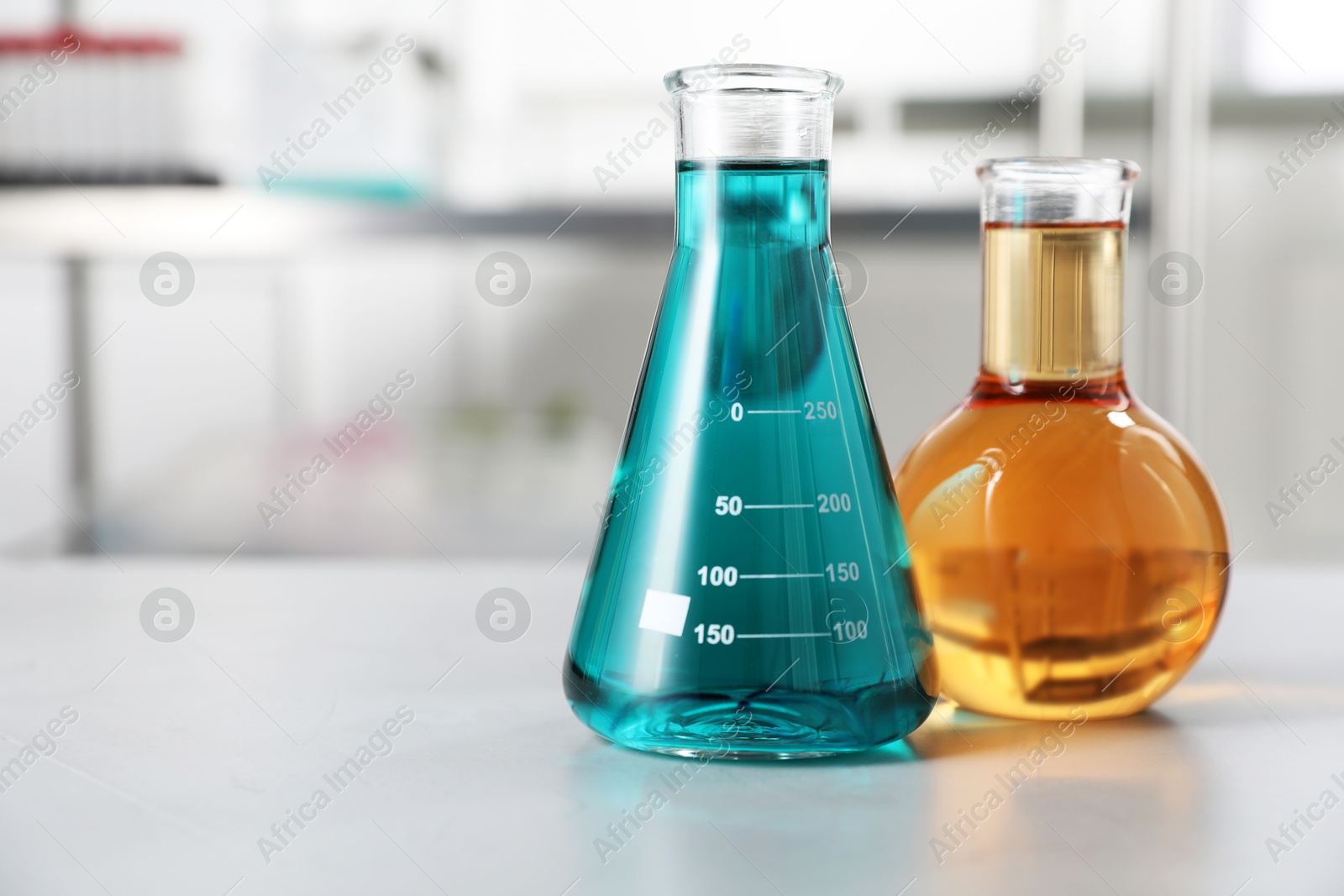 Flasks with color liquids on light table in laboratory. Space for text Photo of Flasks with color liquids on light table in laboratory. Space for text
