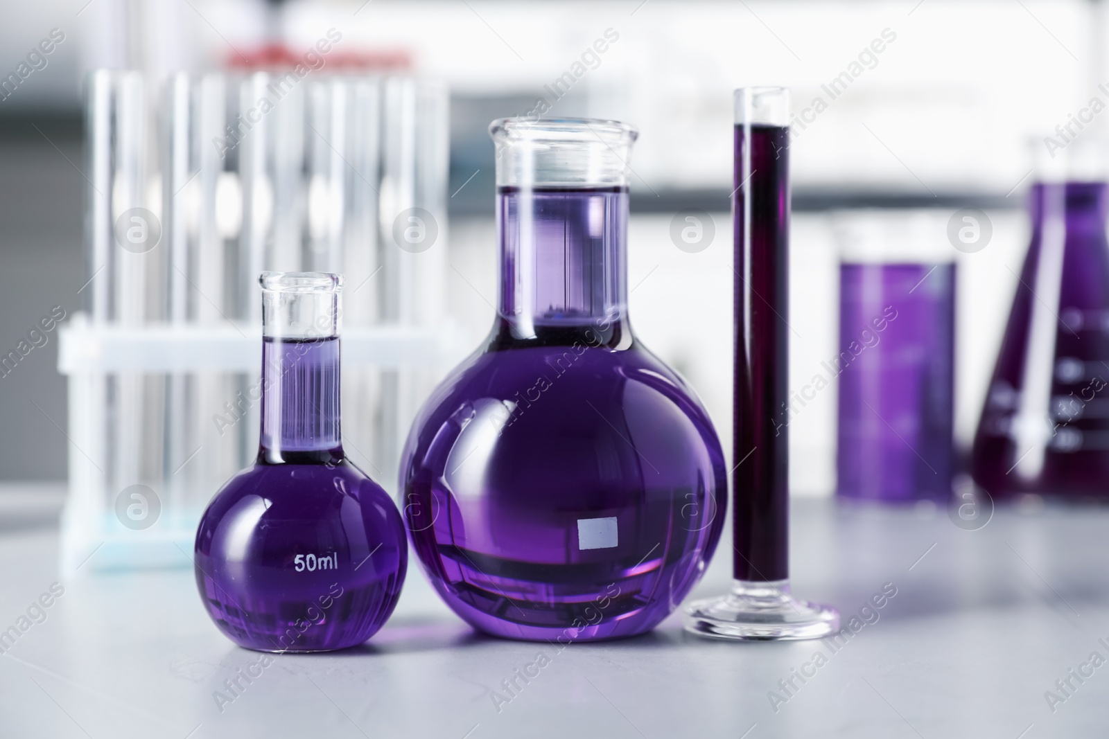 Different laboratory glassware with purple liquid on light table indoors, selective focus Photo of Different laboratory glassware with purple liquid on light table indoors, selective focus