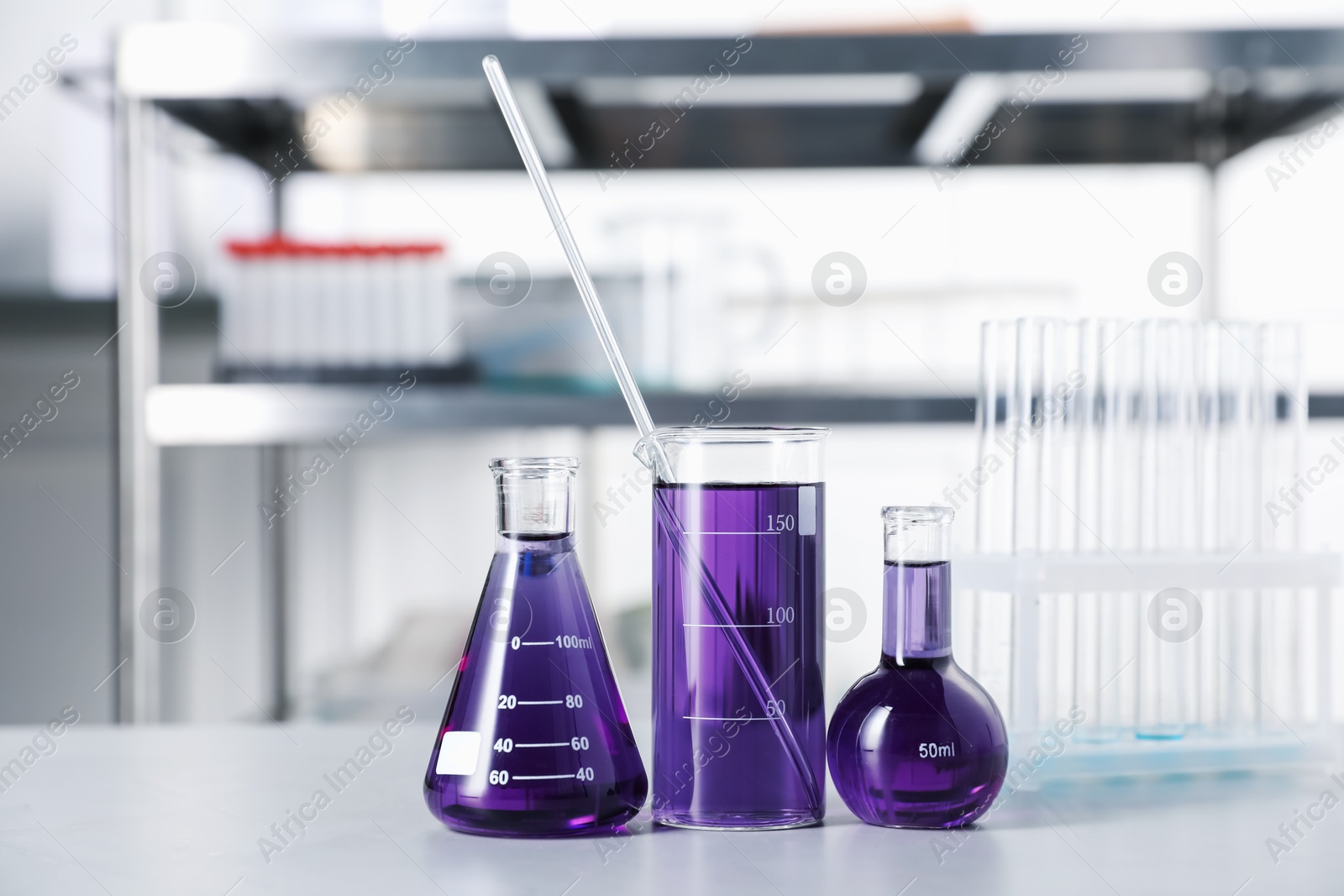 Different laboratory glassware with purple liquid on light table indoors Photo of Different laboratory glassware with purple liquid on light table indoors