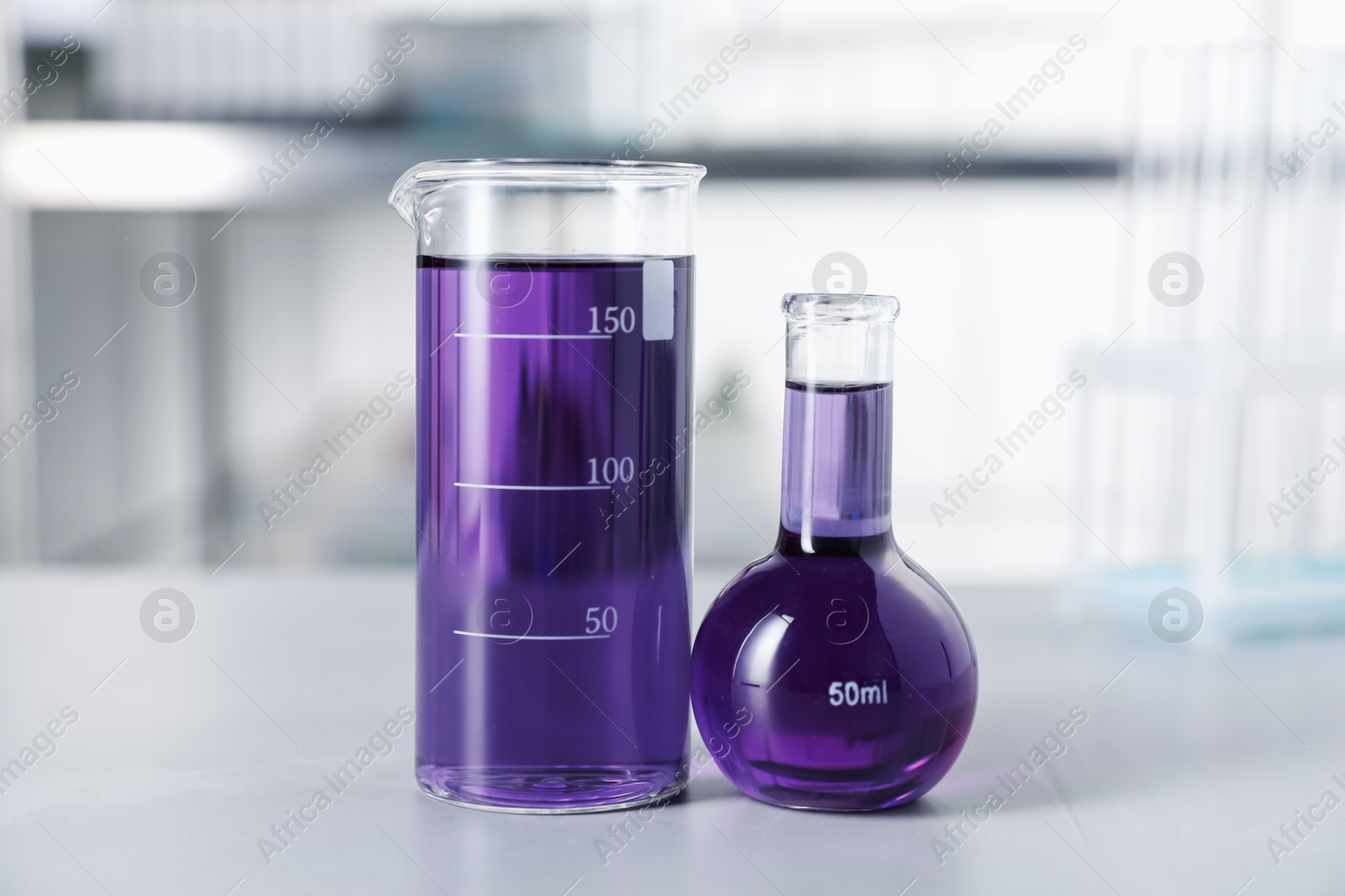 Photo of Laboratory glassware with purple liquid on light table indoors