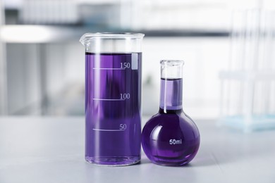 Photo of Laboratory glassware with purple liquid on light table indoors