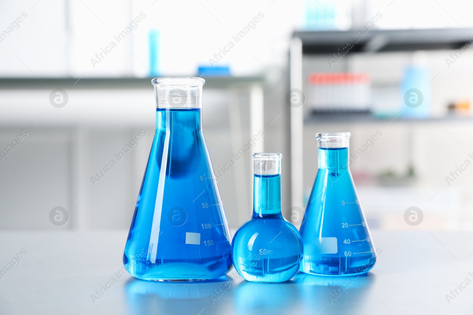 Flasks with light blue liquid on table in laboratory Photo of Flasks with light blue liquid on table in laboratory