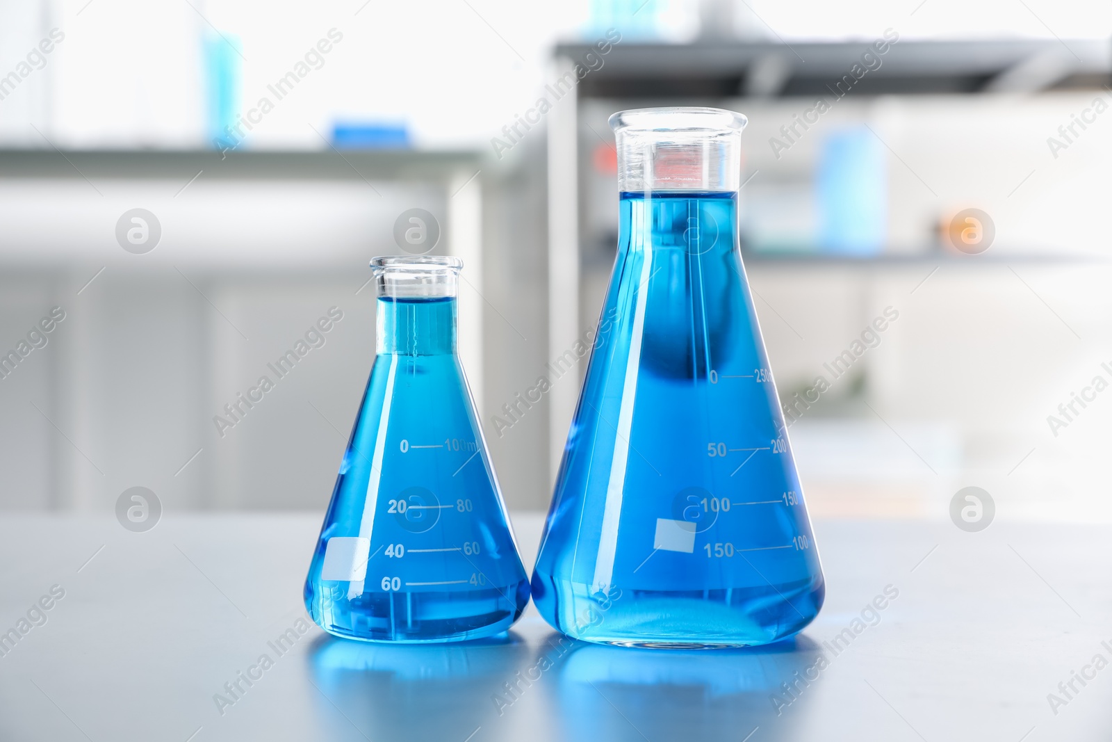 Flasks with light blue liquid on table in laboratory Photo of Flasks with light blue liquid on table in laboratory