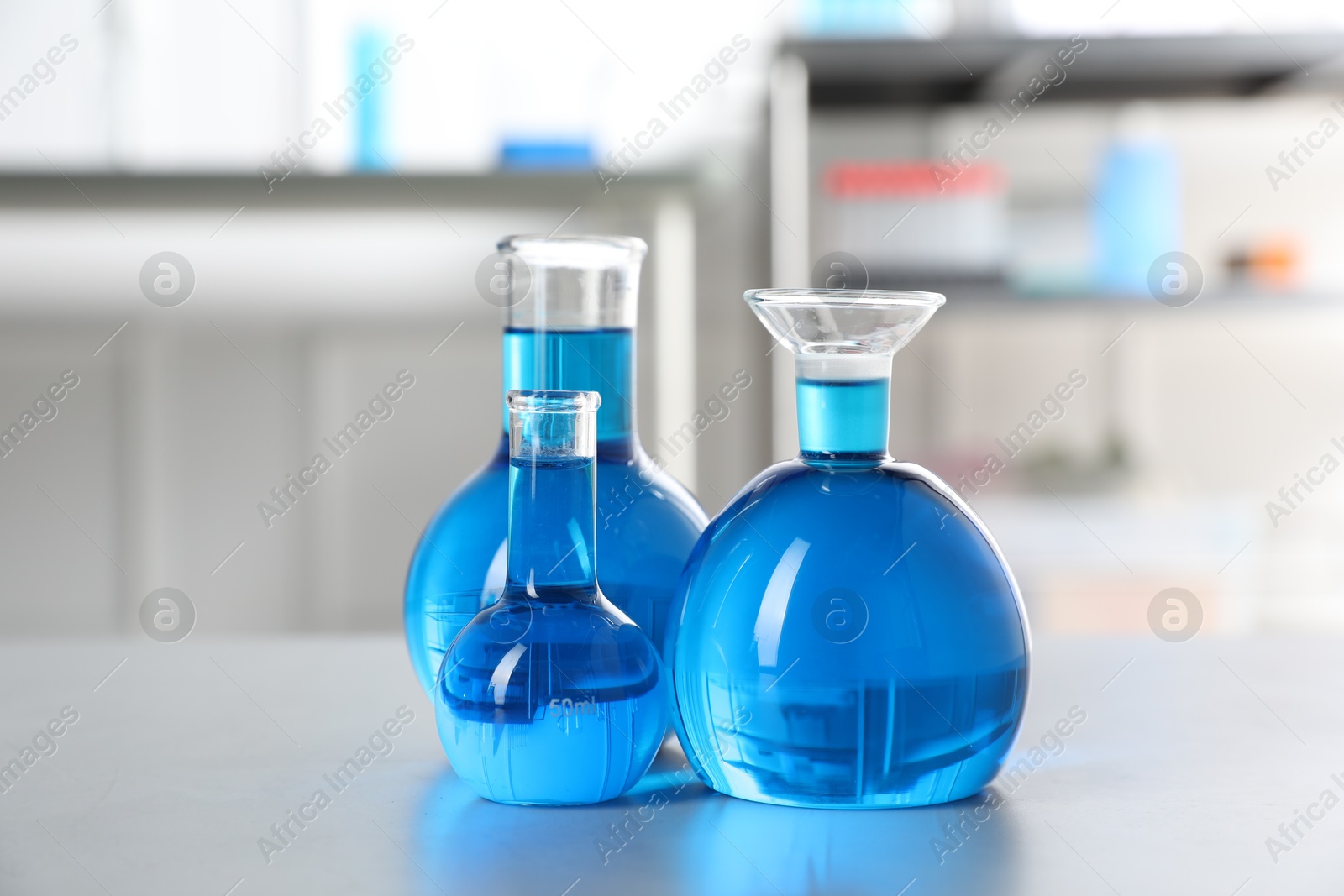 Flasks with light blue liquid on table in laboratory Photo of Flasks with light blue liquid on table in laboratory