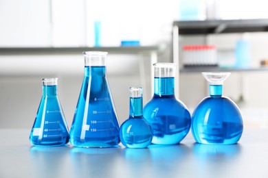 Photo of Different laboratory glassware with light blue liquid on table indoors
