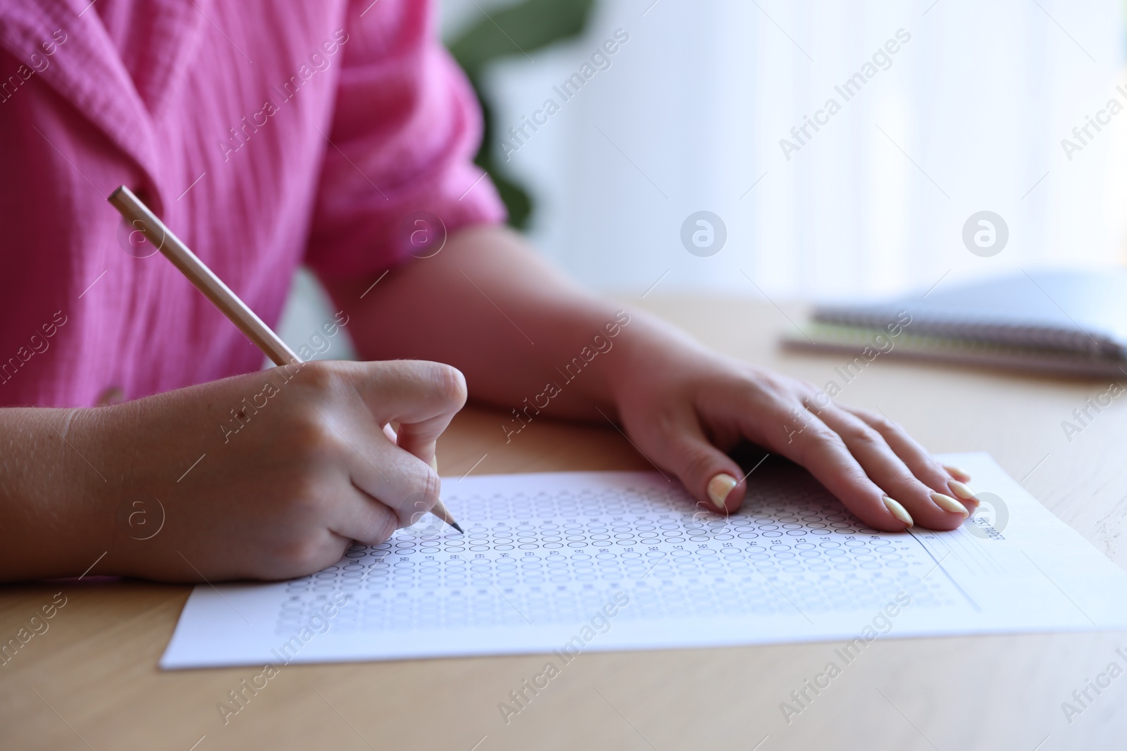 Student filling out multiple choice test at table in class, closeup. Passing exam Photo of Student filling out multiple choice test at table in class, closeup. Passing exam