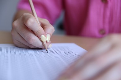 Photo of Student filling out multiple choice test at table, closeup. Passing exam