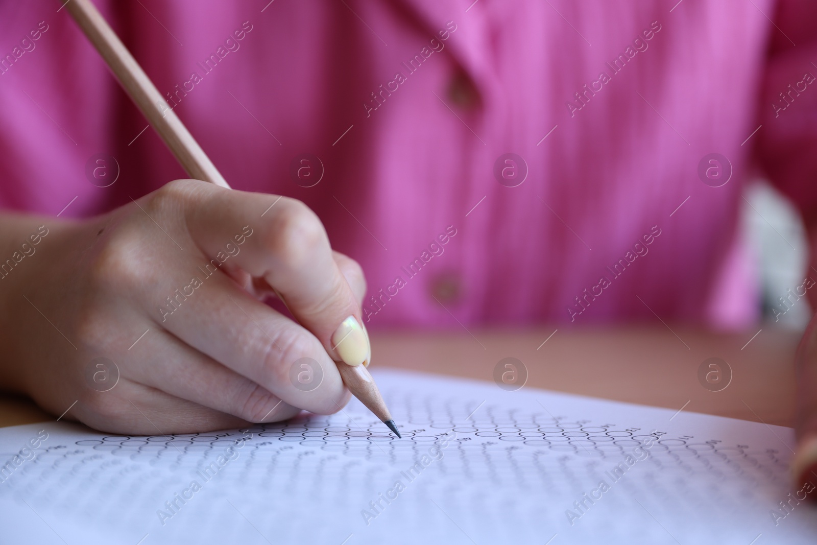 Student filling out multiple choice test at table, closeup. Passing exam Photo of Student filling out multiple choice test at table, closeup. Passing exam