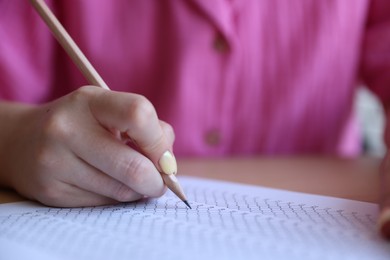 Photo of Student filling out multiple choice test at table, closeup. Passing exam