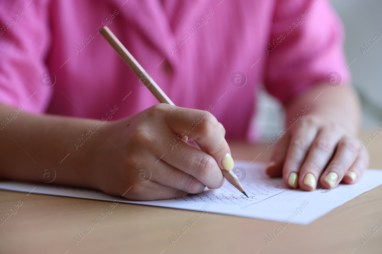 Student filling out multiple choice test at table in class, closeup. Passing exam Photo of Student filling out multiple choice test at table in class, closeup. Passing exam