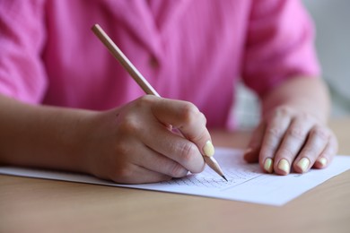 Photo of Student filling out multiple choice test at table in class, closeup. Passing exam